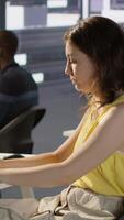 Vertical Manager in wheelchair passing by desk of employee testing machine learning company software to minimize occurrence of bugs. Woman works in inclusive workspace with workers with disabilities, camera A video
