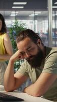 Vertical Exhausted developer caught asleep at desk by manager while developing AI machine learning company tech. Supervisor waking up tired sleeping employee while training predictive models, camera B video
