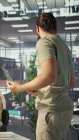 Vertical Cheerful admin holding laptop chatting with colleagues while working with machine learning tech. Man transforming data into predictive models using notebook and talking with coworkers, camera B video