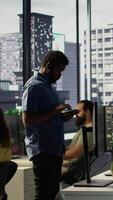 Vertical Computer scientist resuming work after strolling in workspace, doing software debugging using PC. Man walking with tablet in office, fixing coding issues using computer, camera B video