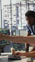 Vertical Manager correcting programmer mistakes while conducting code review to fix errors, identifying technical issues with company software. Team leader supervising IT staff member optimizing code, camera B video