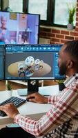 Vertical African american industrial designer works on prototypes in a creative studio. Doing tech driven remote work with 3D modeling and CAD software, industrial tools for technical precision. Camera A. video