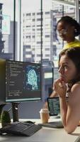 Vertical Hacker in office using laptop to steal company secrets, doing data breach, hiding from manager. Employee hired by competitor to spy, mining info from servers, closing notebook lid to hide, camera B video