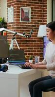 Vertical Asian programmer seen typing code for a user interface design on dual monitors, working in a digital workspace. Woman coder working on software engineering and front end development. Camera A. video