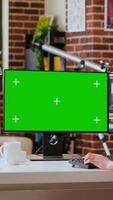 Vertical Female editor working on a creative project shoot, using chroma key copy space screen next to color grading software. Home workspace highlights productivity. Camera B. video