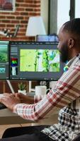Vertical Male creator edits a multimedia project at a modern office, using professional tech tools and editing software to manage timeline editing and production. Work from home. Camera A. video