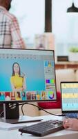 Vertical Asian graphic designer uses editing software for photo retouching in a well organized home workspace. Female freelancer uses digital tools essential for a creative artistic career. Camera B. video