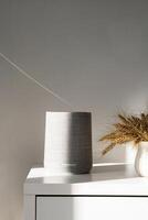 Modern gray speaker on table with soft shadows and light. photo