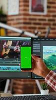 Vertical Male editor works on a movie project in a creative software next to chroma key, multitasking between timeline editing and color grading using dual monitors and tech tools. Camera B. video
