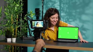 Woman filming herself watching internet videos on mockup laptop requested by viewers. Online influencer reacting to online clips sent by subscribers using green screen notebook, camera A