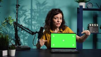 Woman in home studio using recording tech to capture live broadcast, reviewing mockup laptop. Internet show host filming electronics haul, presenting isolated screen notebook for viewers, camera B video