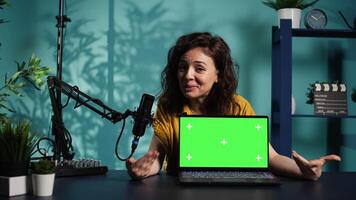 Happy content creator being sponsored by partnering brand to do green screen laptop unboxing. Upbeat technology guru does influencer marketing, doing mockup notebook product placement, camera B video