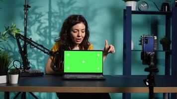 Influencer in home studio using recording tech to capture live broadcast, reviewing chroma key laptop. Online show host filming electronics haul, presenting green screen notebook for viewers, camera B video