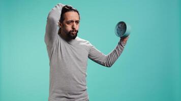 Portrait of worried man looking at alarm clock, stressed after not hearing ring and waking up late in the morning. Anxious person running out of time, isolated over studio background, camera B video