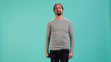 Assertive man doing stop hand gesture sign, studio backdrop. Annoyed person doing firm halt sign gesturing, wishing to end concept, isolated over blue studio background, camera A video