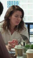 Vertical General director sharing insight about a new expansion strategy with her employees, presenting data reports to analyze business activity status. Coworkers in a briefing meeting. Camera A. video