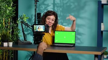 Media star reviews newly launched chroma key gaming laptop, comparing features with older models. Internet show host filming for social media, analyzing green screen notebook video