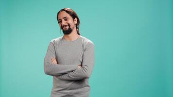Portrait of joyous man holding hands together, smiling, looking pleased, isolated over studio background. Upbeat person dressed casually exulting, feeling satisfied, camera B video
