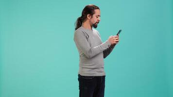 Smiling man having friendly conversation with friends during teleconference meeting using smartphone, studio background. Person having fun catching up with mates during online videocall, camera A video