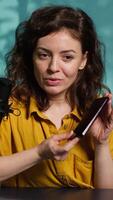 Vertical Smartphone on holder capturing footage of reviewer discussing with viewers about newly released cellphone. Influencer chats with fans during stream, filming latest generation phone review, camera A video