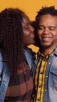 Vertical Affectionate romantic wife whispering intimate things to her husband, caressing and telling a secret into his ear. Cute optimistic couple flirting with each other, laughing in studio. Camera A. video