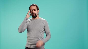 Portrait of man feeling exhausted from overworking, suffering from headache, isolated over studio background. Tired person feeling pain from fatigue, studio backdrop, camera B video