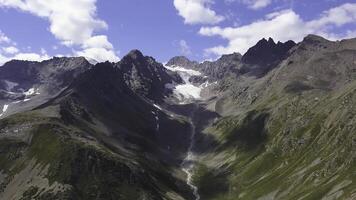 Awesome aerial view to big snowy rocky mountains under blue sky. Clip. Wonderful scenery with giant mountains with green slopes and white peaks and the gorge between two ranges. photo