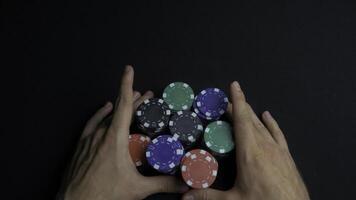 Stack of poker chips and two hands on table. Closeup of poker chips in stacks on green felt card table surface. Poker chips and hands above it on green table. Dealer photo