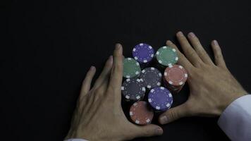 Stack of poker chips and two hands on table. Closeup of poker chips in stacks on green felt card table surface. Poker chips and hands above it on green table. Dealer photo