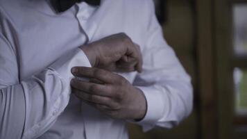 Man buttoning on the sleeves of the shirt. Close up of a hand man how wears white shirt and cufflink. Man buttoning on the sleeve of his shirt. Zip up the cufflink. Men's style. photo