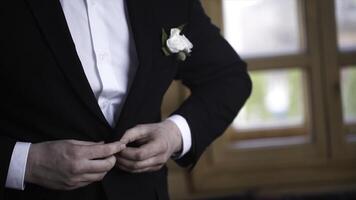 Man buttoning on a black jacket. Wedding details - elegant groom dressed wedding tuxedo costume is waiting for the bride. businessman buttoning jacket, getting dressed. Groom buttons jacket photo