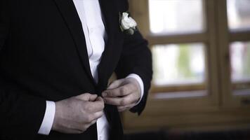 Man buttoning on a black jacket. Wedding details - elegant groom dressed wedding tuxedo costume is waiting for the bride. businessman buttoning jacket, getting dressed. Groom buttons jacket photo