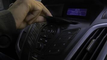 Man's hand puts the disk into the car player. Button control for compact disk player in a car. Hand puts the disk into the radio car photo
