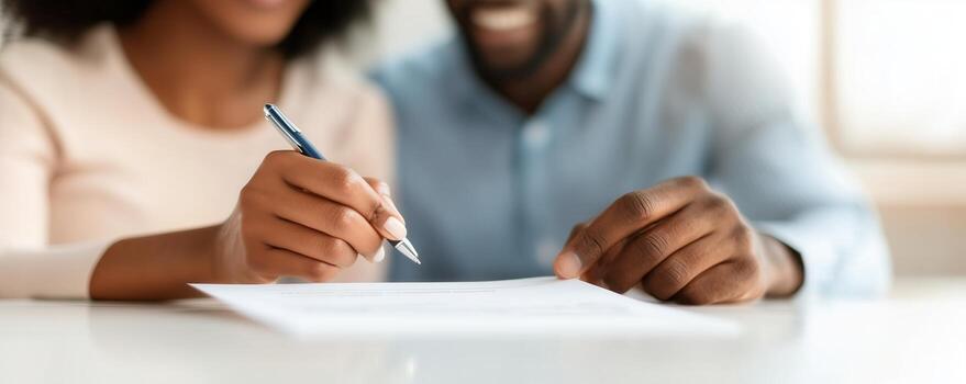 A close-up of a couple signing important documents together, showcasing teamwork and collaboration in a professional setting, with focus on their hands and paperwork. photo