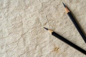 Two black pencils are on a paper with a rough texture photo