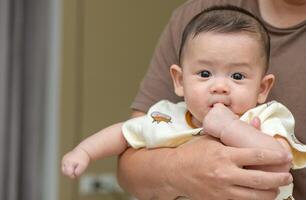 Asian infant baby open mouth and putting fingers in to sucking feel secure. photo