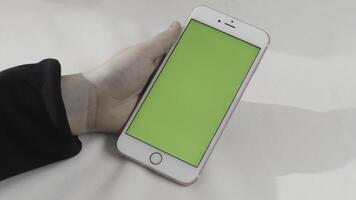 Hand holding touch green screen smart phone on white background. Stock footage. Hand with a cell phone with chroma key. photo