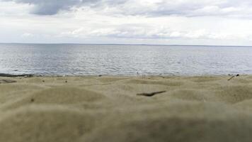 River bank with sand dunes and rippled waterof river on the background. Concept. Close up of sandy shore of a wide river against mountains and cloudy sky. photo