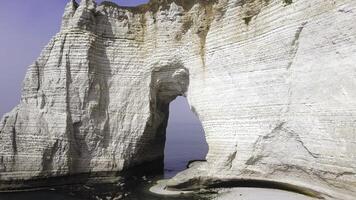 Aerial for the beautiful arch in white rock above the calm sea in a summer sunny day, forms and shapes of nature. Action. Arch in the cliff above water. photo