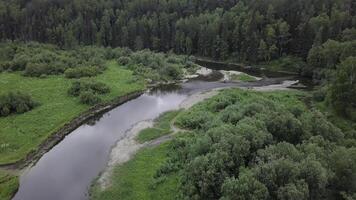 Top view of panorama of river passing through forest. Stock footage. Beautiful view of river reflecting sky and surrounding forest photo