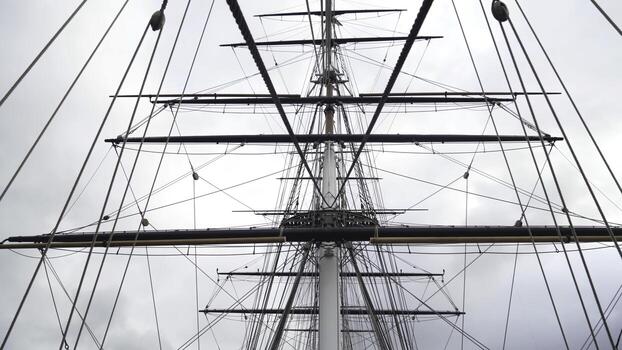 Masts and cables of ship on background of cloudy sky. Action. Towering masts with many intertwined cables and ropes of sailing ship on background of cloudy sky photo