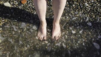 Top view of feet at the beach with sea waves. Concept. Connecting to nature, beautiful legs and feet of a woman with her nails painted black being washed by sea or ocean waves. photo