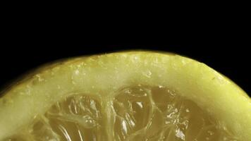 A single fresh yellow lemon on a wood grain table against a black background. Fresh sliced lemon on the black background, macro photo