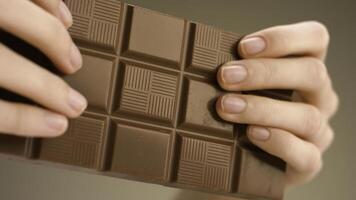 Man breaking chocolate. Stock footage. Close-up of hands breaking chocolate bar into two parts. Delicious chocolate is broken into pieces on isolated background photo