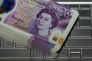 Stack of Twenty Pound Notes on Laptop Keyboard photo