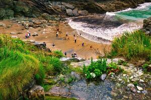 Scenic Beach View with People and Rocky Cliffs in Tintagel, Cornwall, UK photo