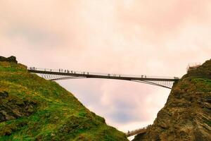 Bridge Connecting Cliffs with People Walking in Tintagel, Cornwall, UK photo