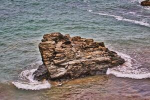 Rugged Rock Formation in Ocean Waves in Tintagel, Cornwall, UK photo