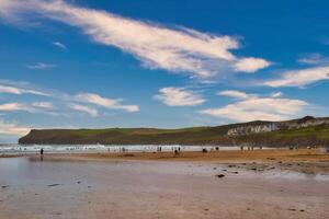 Scenic Beach with People and Hills in Cornwall, UK photo