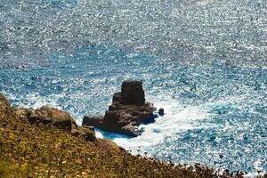 Rocky Outcrop in Shimmering Ocean at Land's End in Cornwall, UK photo